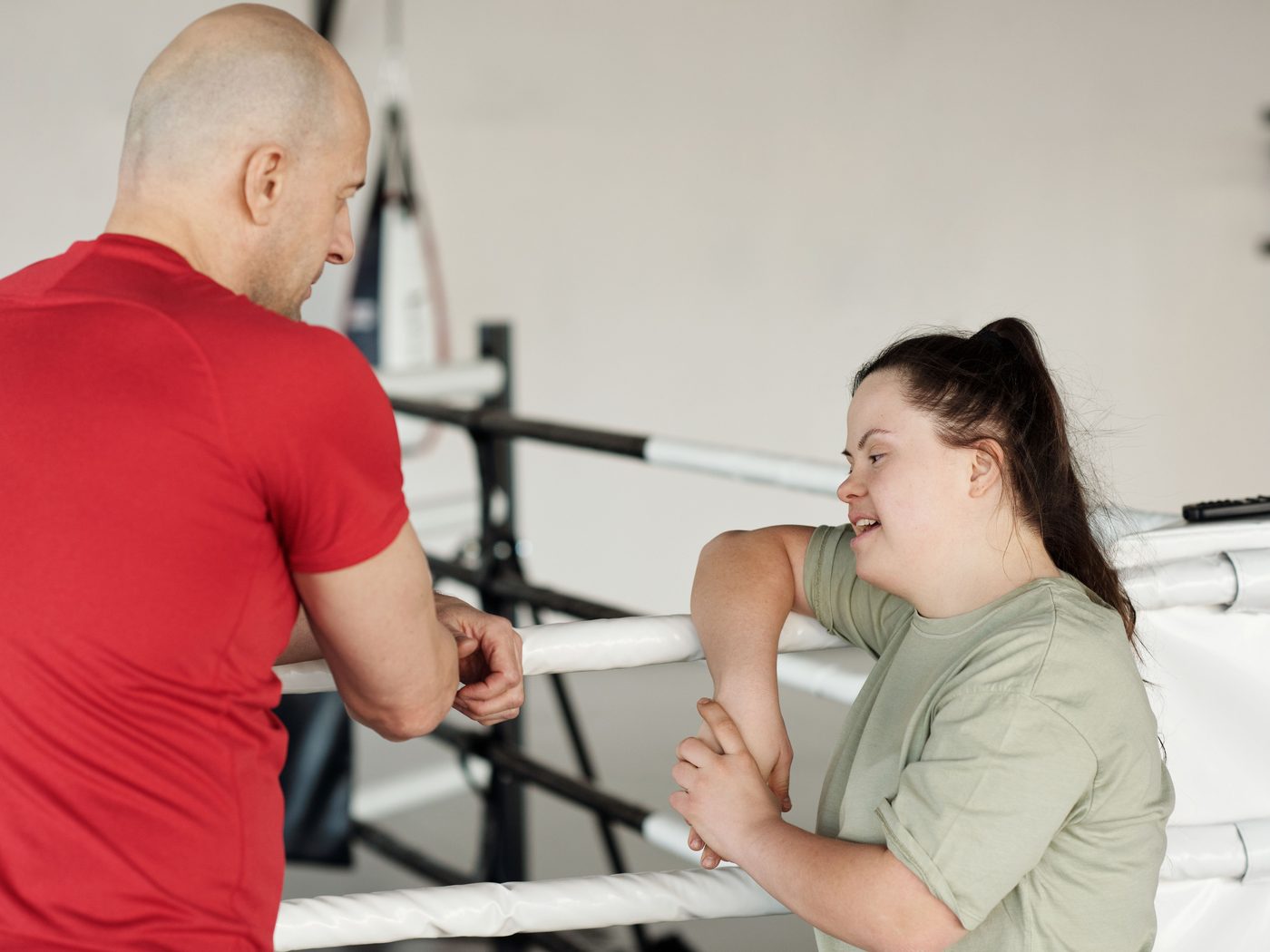 A woman with Down syndrome talking with her coach beside a boxing ring
