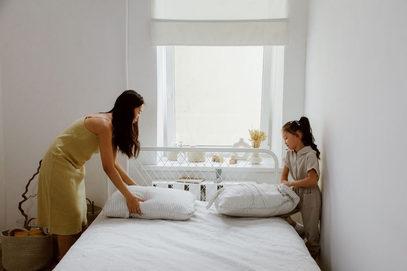 A mother and daughter making the bed together at home